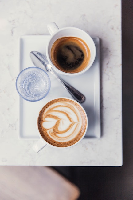 Ein gutes Gedeck um Espresso richtig trinken zu können. Auf einem Tablet stehen ein Espresso, Espresso Löffel, Glas Wasser.