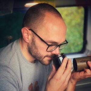 Horst von einfach mal Kaffee sitzt in seinem Camper Van und riecht genussvoll an frisch gemahlenem Kaffee. Riechen ist der wichtigste Teil unserer Kaffee Sensorik, zu erlernen auch in einem Sensorik Kurs.