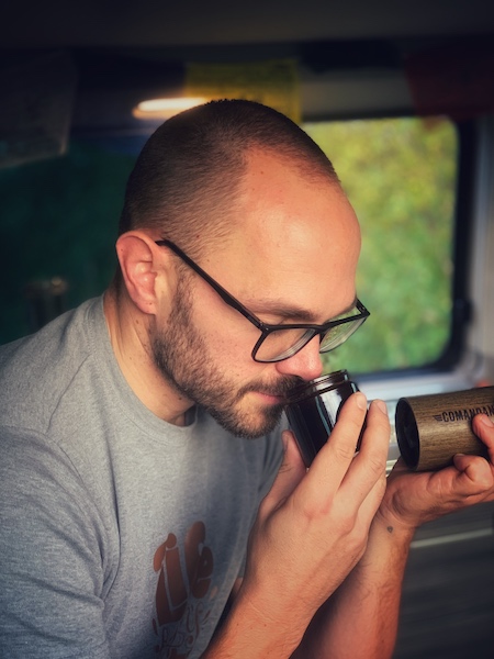 Horst von einfach mal Kaffee sitzt in seinem Camper Van und riecht genussvoll an frisch gemahlenem Kaffee. Riechen ist der wichtigste Teil unserer Kaffee Sensorik, zu erlernen auch in einem Sensorik Kurs.