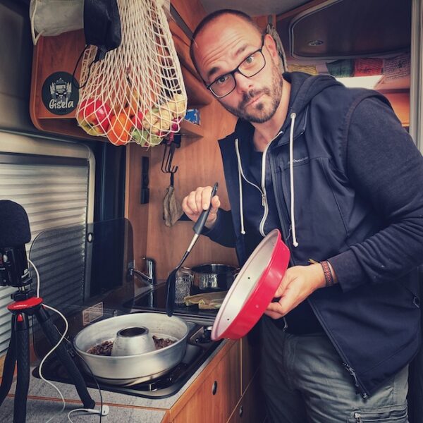 Horst steht in seinem Wohnmobil und röstet Kaffee im Omnia Camping Ofen.
