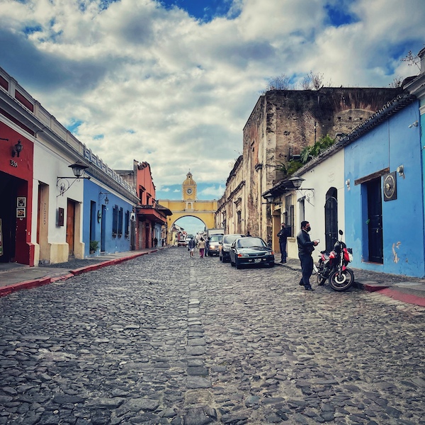 Der berühmte Torbogen von Antigua Guatemala, vor einer leeren Straße mit bunten Häusern.
