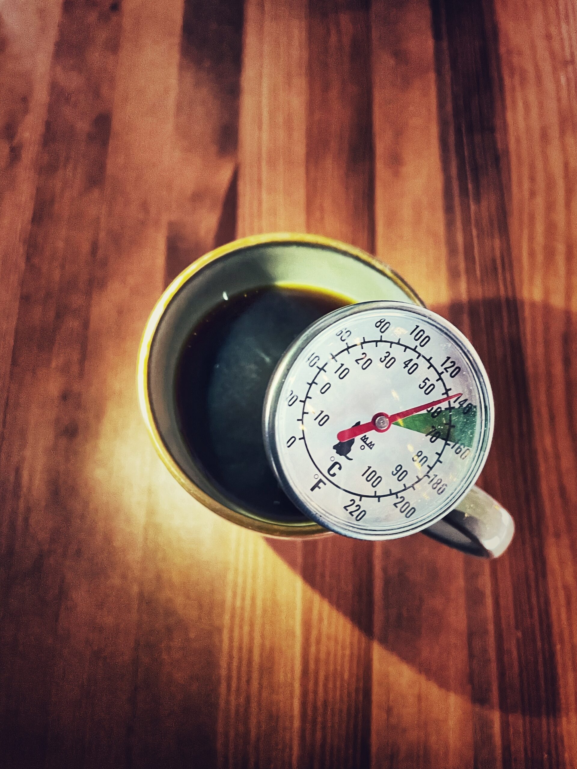 Tasse Kaffee mit Thermometer, beantwortet die frage wie heiss kaffee sein darf
